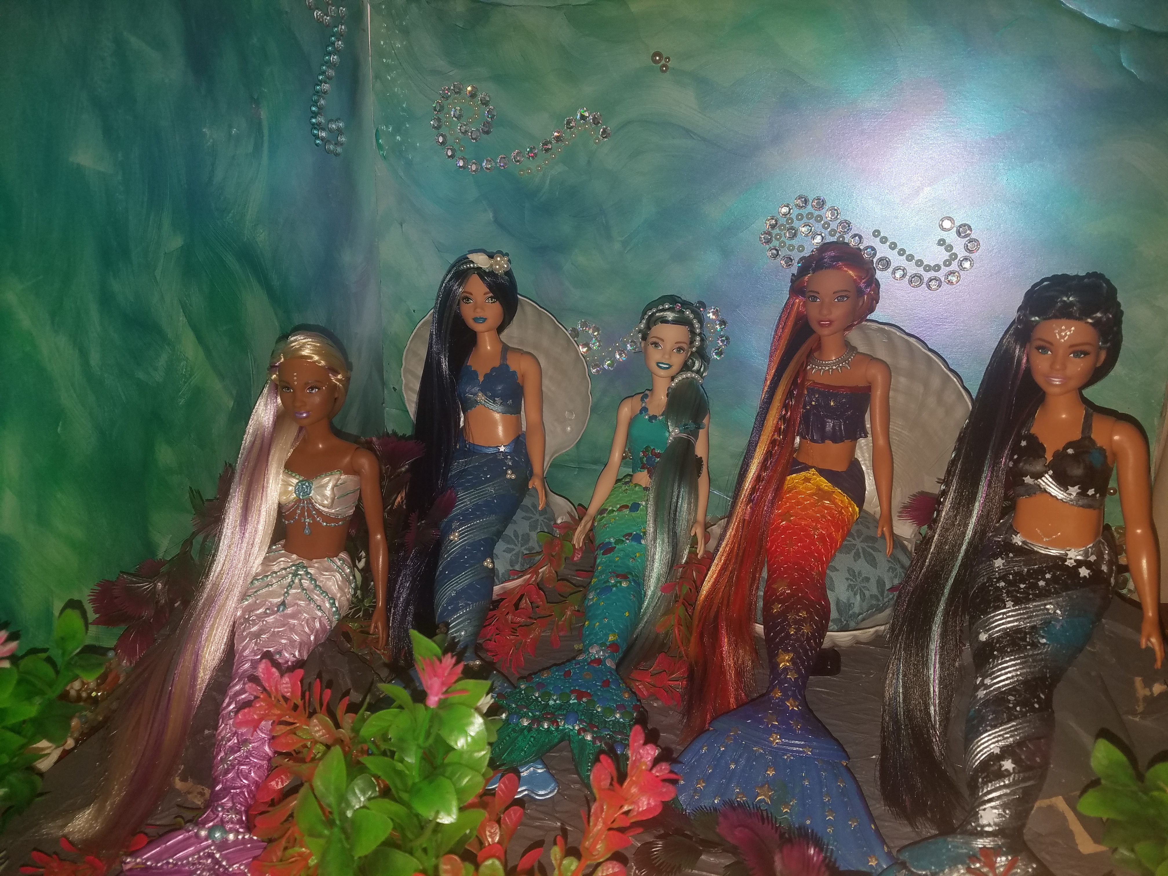 Dreamtopia Mermaid Barbie repaints, Left to Right, Purple and White, then Blue, green and silver, then blue and green, then sunset colors, then night sky dark blue with silver, purple and white accents. All have long hair nearly to the bottom of their tail fins.