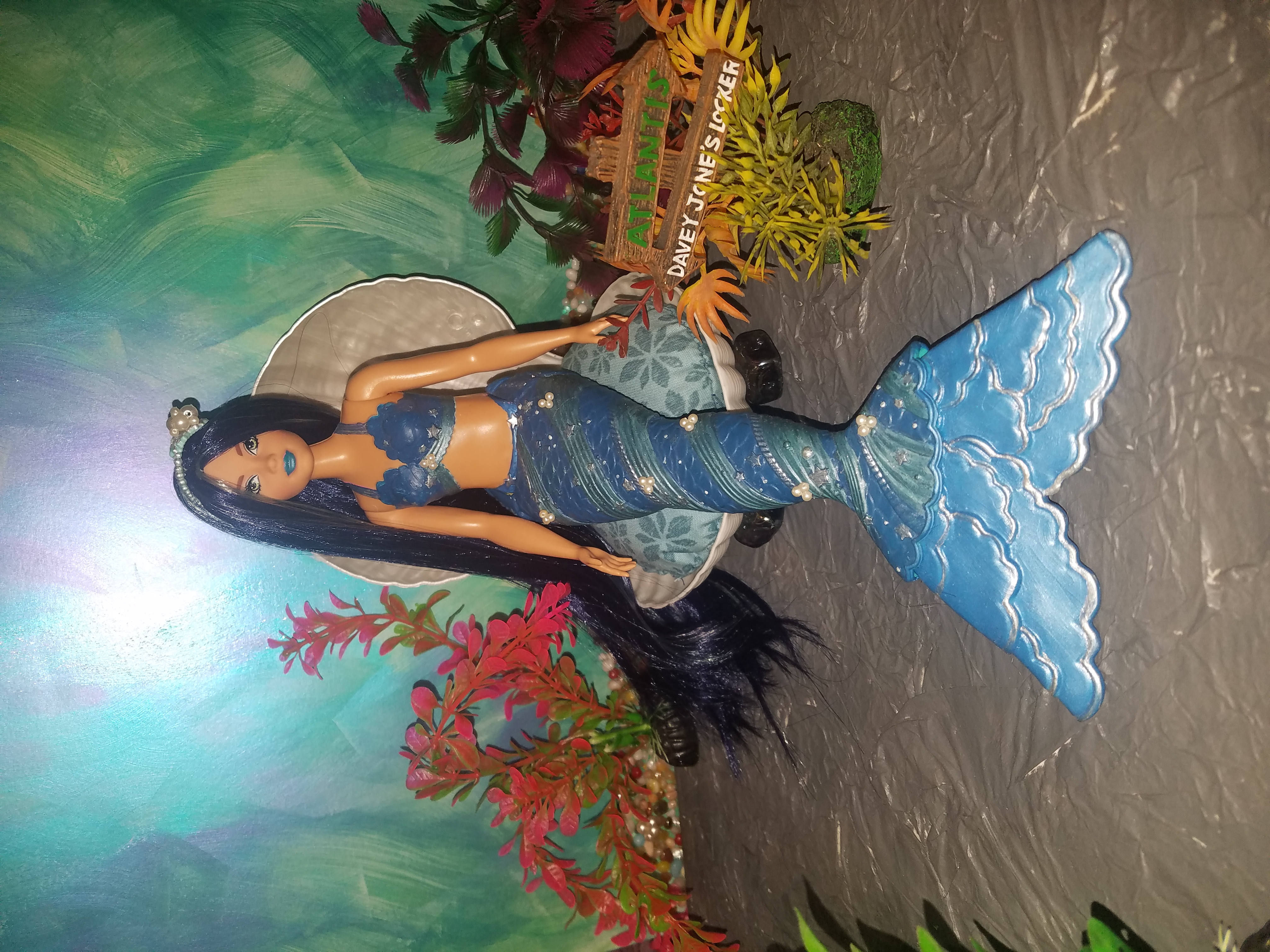 Dreamtopia Curvy mermaid Barbie, her tail is dark blue-green with blue and silver accents, her hair dark blue, blue green and silver to match.